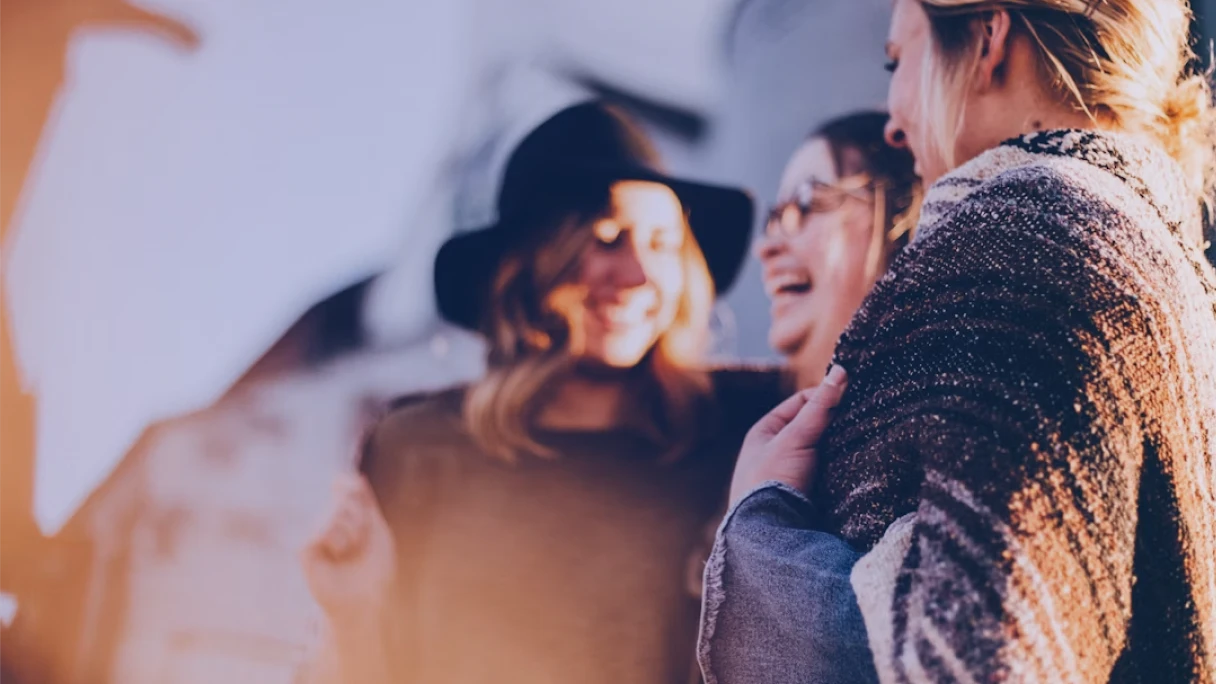 Grupo de mulheres conversando e rindo em um momento de acolhimento, ilustrando a conexão entre saúde mental e voluntariado corporativo